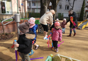 Dzieci witają wiosnę w ogródku przedszkolnym.