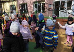 Dzieci witają wiosnę w ogródku przedszkolnym.