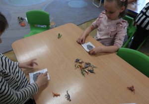 Dzieci wykonują odciski dinozaurów w masie plastycznej.