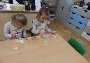 Dzieci przy stolikach i przeprowadzają doświadczenia z wodą.
