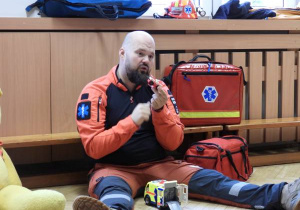 Ratownik medyczny opowiada dzieciom o udzielaniu pierwszej pomocy.