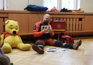 Ratownik medyczny opowiada dzieciom o udzielaniu pierwszej pomocy.