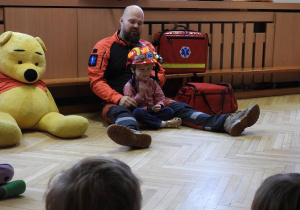 Ratownik medyczny opowiada dzieciom o udzielaniu pierwszej pomocy.