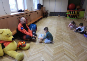 Ratownik medyczny opowiada dzieciom o udzielaniu pierwszej pomocy.