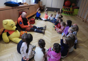 Ratownik medyczny opowiada dzieciom o udzielaniu pierwszej pomocy.