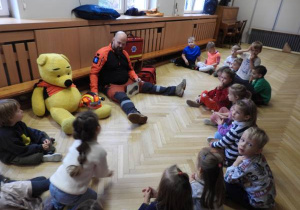 Ratownik medyczny opowiada dzieciom o udzielaniu pierwszej pomocy.