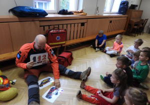 Ratownik medyczny opowiada dzieciom o udzielaniu pierwszej pomocy.