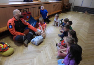 Ratownik medyczny opowiada dzieciom o udzielaniu pierwszej pomocy.