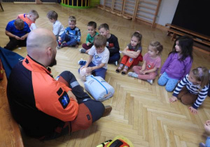Ratownik medyczny opowiada dzieciom o udzielaniu pierwszej pomocy.