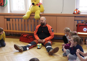 Ratownik medyczny opowiada dzieciom o udzielaniu pierwszej pomocy.