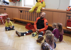 Ratownik medyczny opowiada dzieciom o udzielaniu pierwszej pomocy.