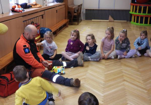 Ratownik medyczny opowiada dzieciom o udzielaniu pierwszej pomocy.