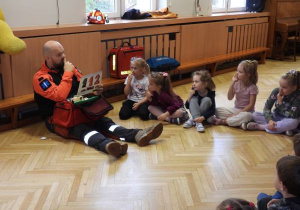 Ratownik medyczny opowiada dzieciom o udzielaniu pierwszej pomocy.