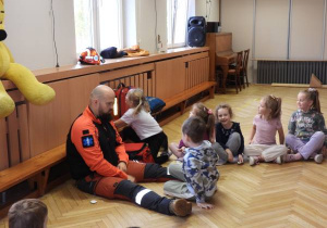 Ratownik medyczny opowiada dzieciom o udzielaniu pierwszej pomocy.