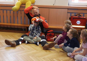 Ratownik medyczny opowiada dzieciom o udzielaniu pierwszej pomocy.