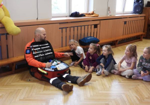 Ratownik medyczny opowiada dzieciom o udzielaniu pierwszej pomocy.