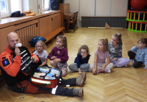 Ratownik medyczny opowiada dzieciom o udzielaniu pierwszej pomocy.