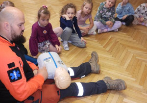 Ratownik medyczny opowiada dzieciom o udzielaniu pierwszej pomocy.