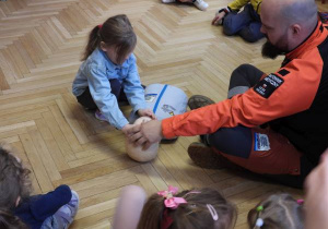 Ratownik medyczny opowiada dzieciom o udzielaniu pierwszej pomocy.