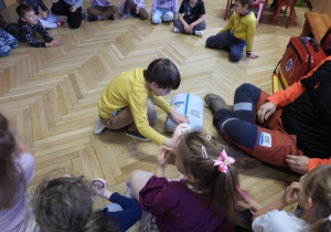 Ratownik medyczny opowiada dzieciom o udzielaniu pierwszej pomocy.