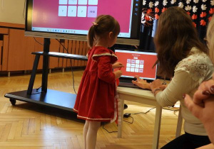 Dziewczynka rozwiązuje quiz na tablicy multimedialnej.