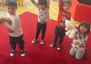 Dzieci stoją na dywanie w rękach trzymają pluszowe zabawki.