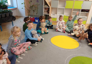 Cdzieci siedzą na dywanie.