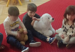 Dzieci siedzą na dywanie.