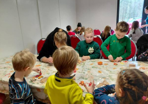 Dzieci malują farbami ozdoby świąteczne.