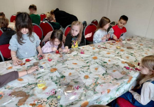 Dzieci malują farbami ozdoby świąteczne.