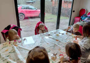 Dzieci malują farbami ozdoby świąteczne.